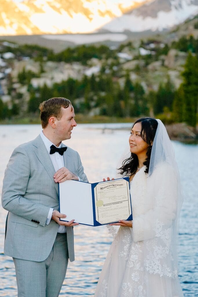 bride and groom holding their marriage license and smiling at each other after their self-solemnization ceremony during their breckenridge elopement in colorado