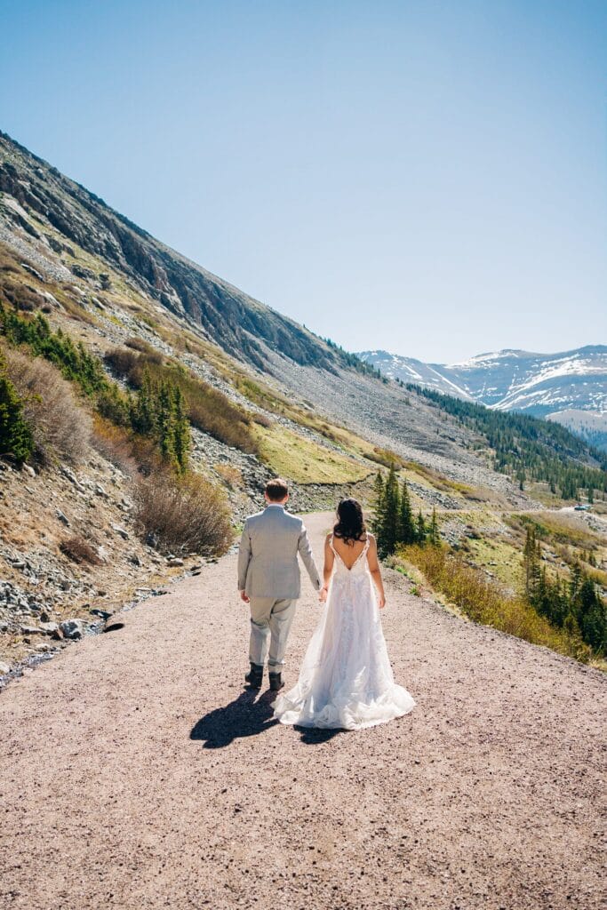 bride and groom holding hands and walking away from the camera