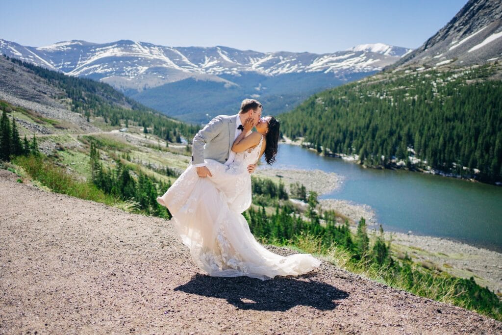 bride and groom kissing as groom dips her back on the edge of a cliff with a lake and mountains in the background during their breckenridge elopement