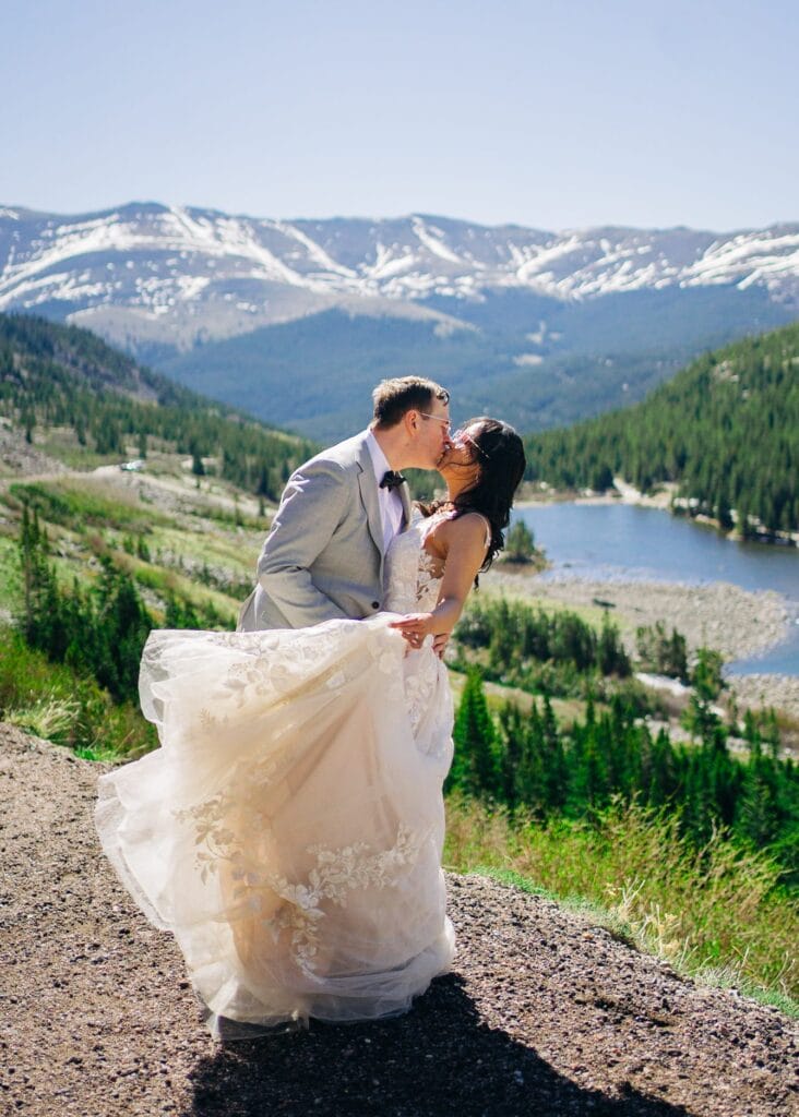 bride and groom kissing while she swings her dress around
