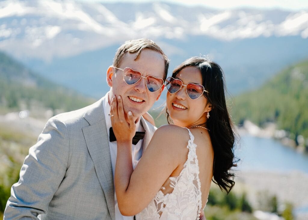 bride and groom smiling at the camera wearing heart sunglasses after their self-solemnization ceremony in breckenridge colorado