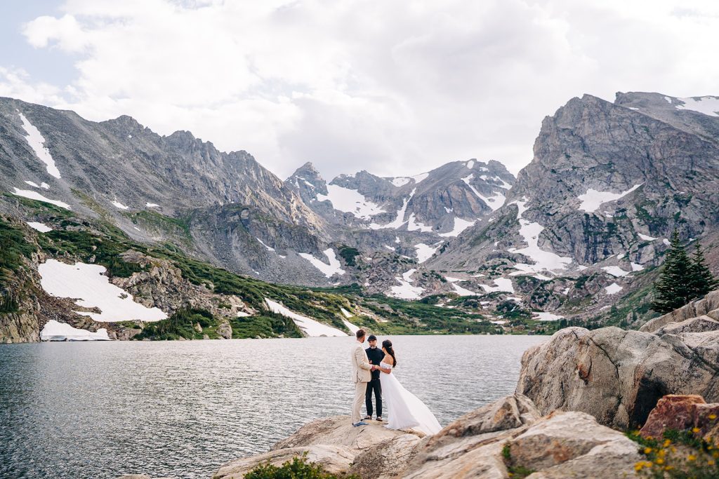 bride and groom holding hands while officiant reads them their vows during their lake isabelle elopement in Colorado with Brenna Nicole Photography