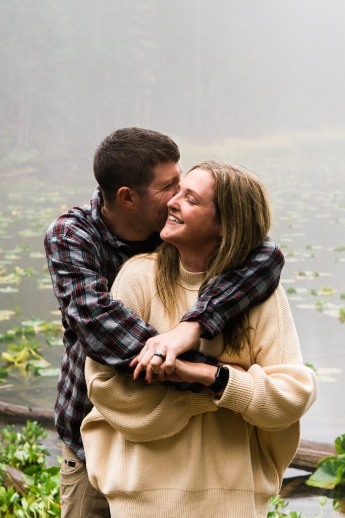 husband kissing wife on the temple during their rocky mountain national park engagement session
