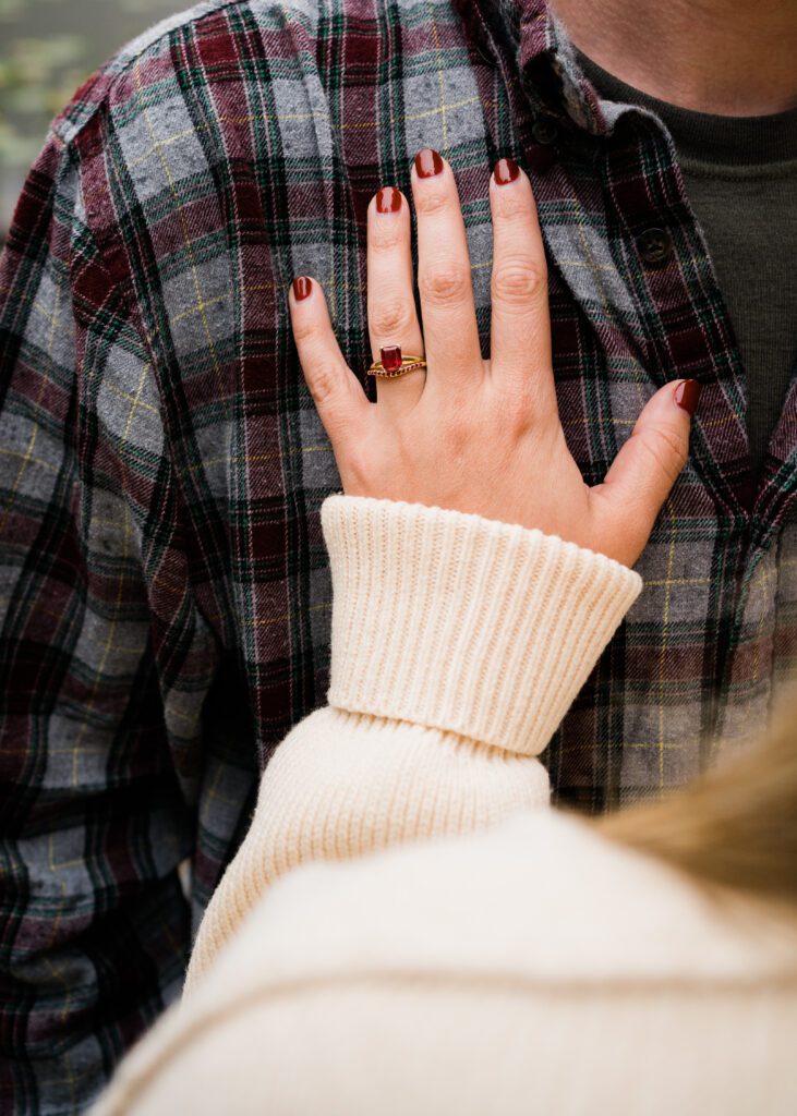 A woman's hand with a ruby engagement ring on her partner's chest