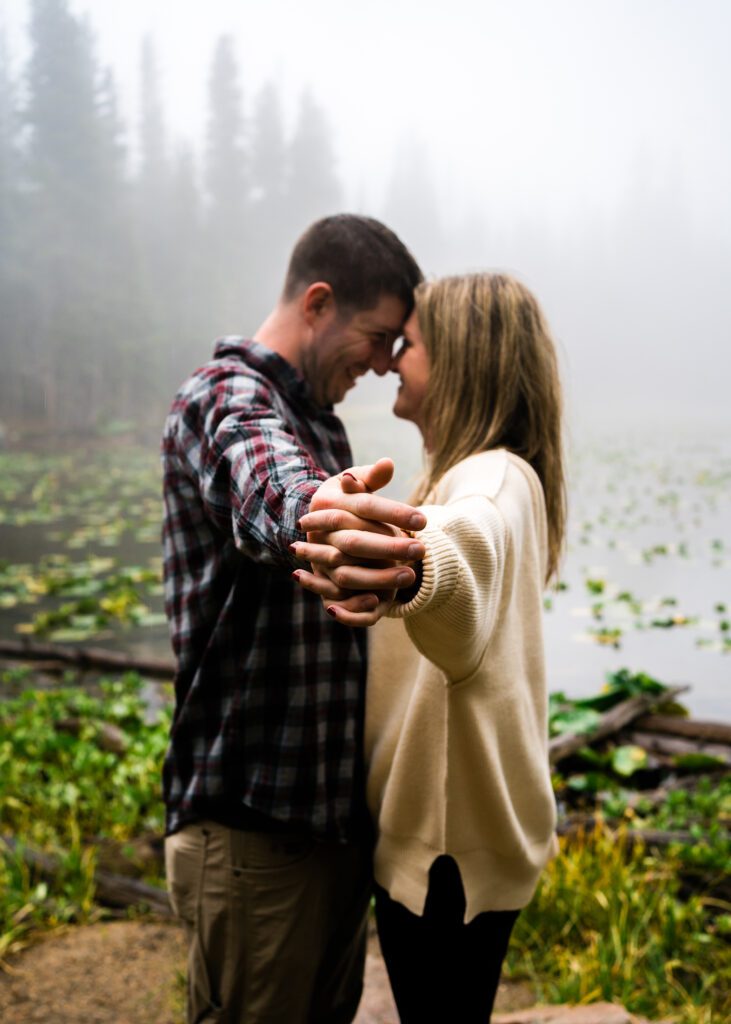 husband and wife holding hands lifted up in the forest during their rocky mountain national park engagement session