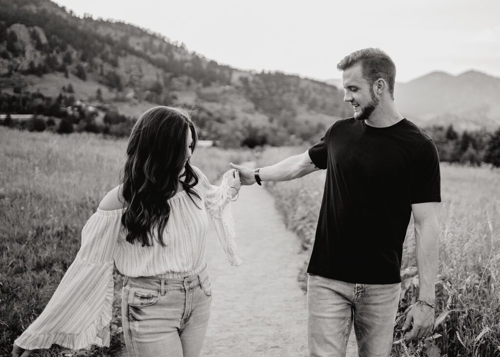 couples being playful and swinging the arms as they walk down a path together at chautauqua park in boulder colorado