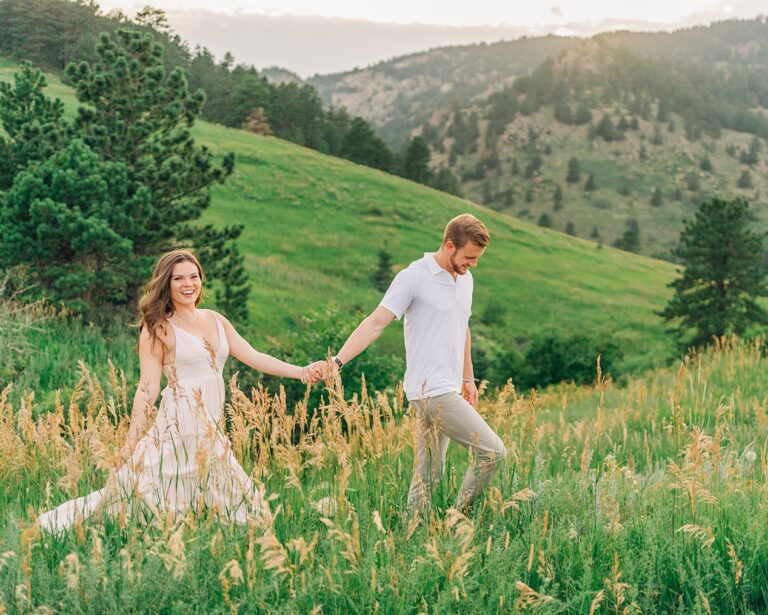 boyfriend leading his girlfriend through a field at chautauqua park during their boulder colorado couples photoshoot