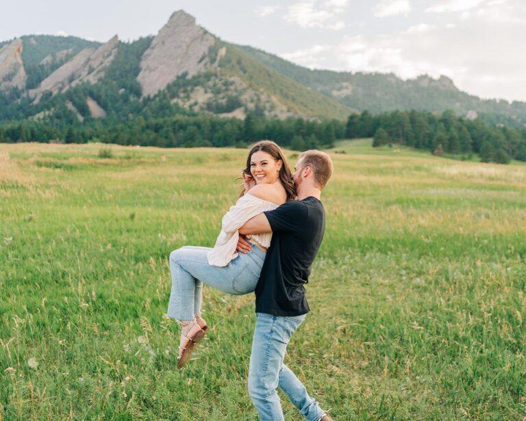 boyfriend spinning his girlfriend around in a circle in a field at chautauqua park in boulder colorado