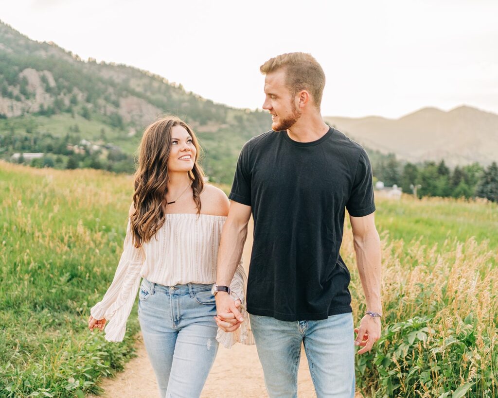 adorable couple holding and hands and walking down a path at chautauqua park during their boulder colorado couples session