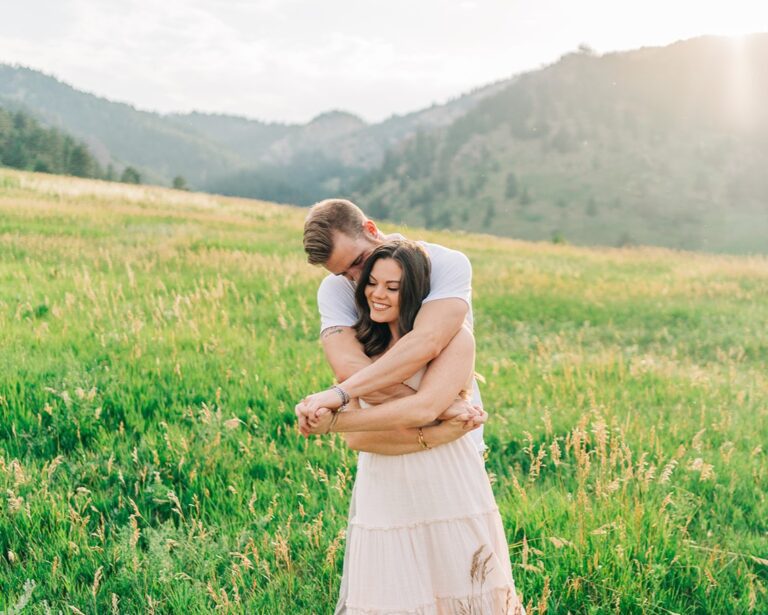 A man hugs his fiance from behind during their engagement portraits at Flatirons in Colorado