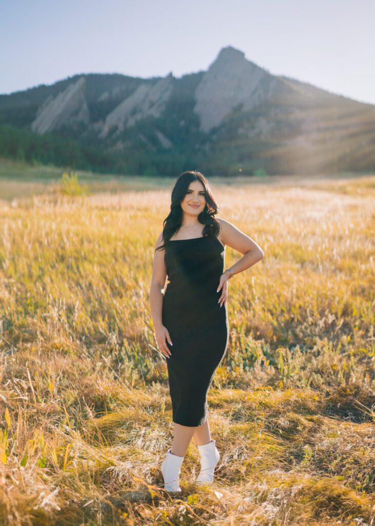 photo of a beautiful latina women standing in a field wearing a black dress at Chautauqua park in boulder colorado