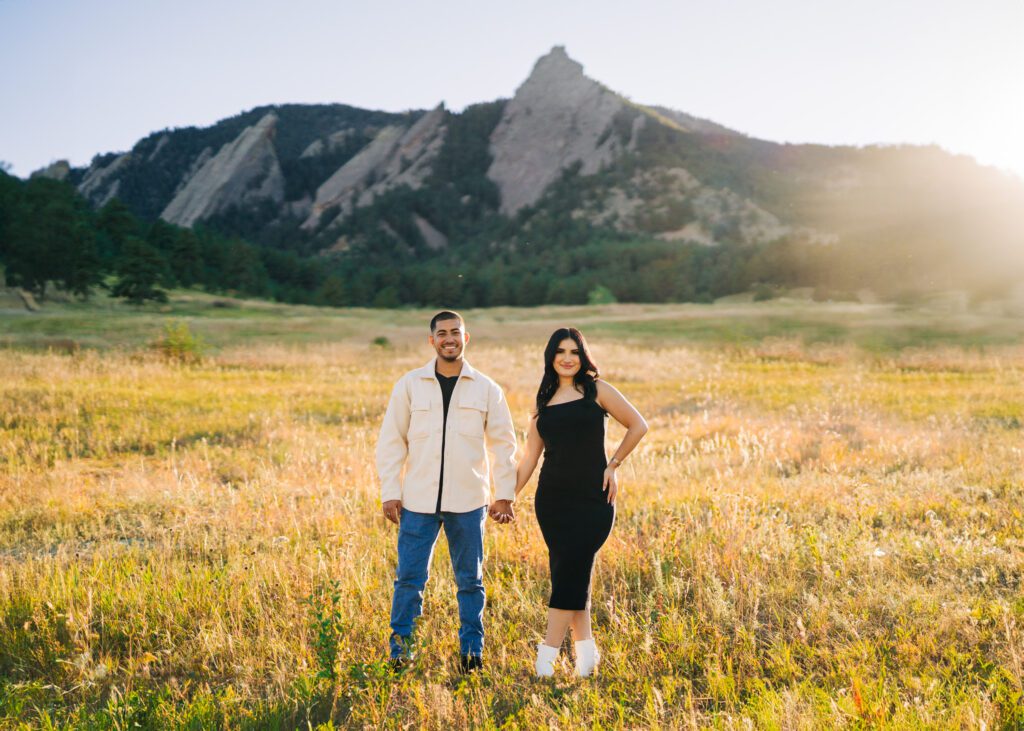 Engaged couple, holding hands before a mountain range, during their engagement photos at Lost Gulch Overlook