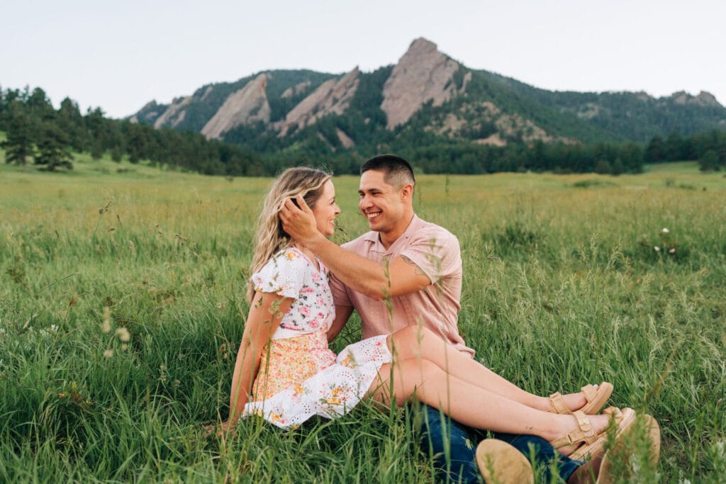 Couple sitting in field with mountains background