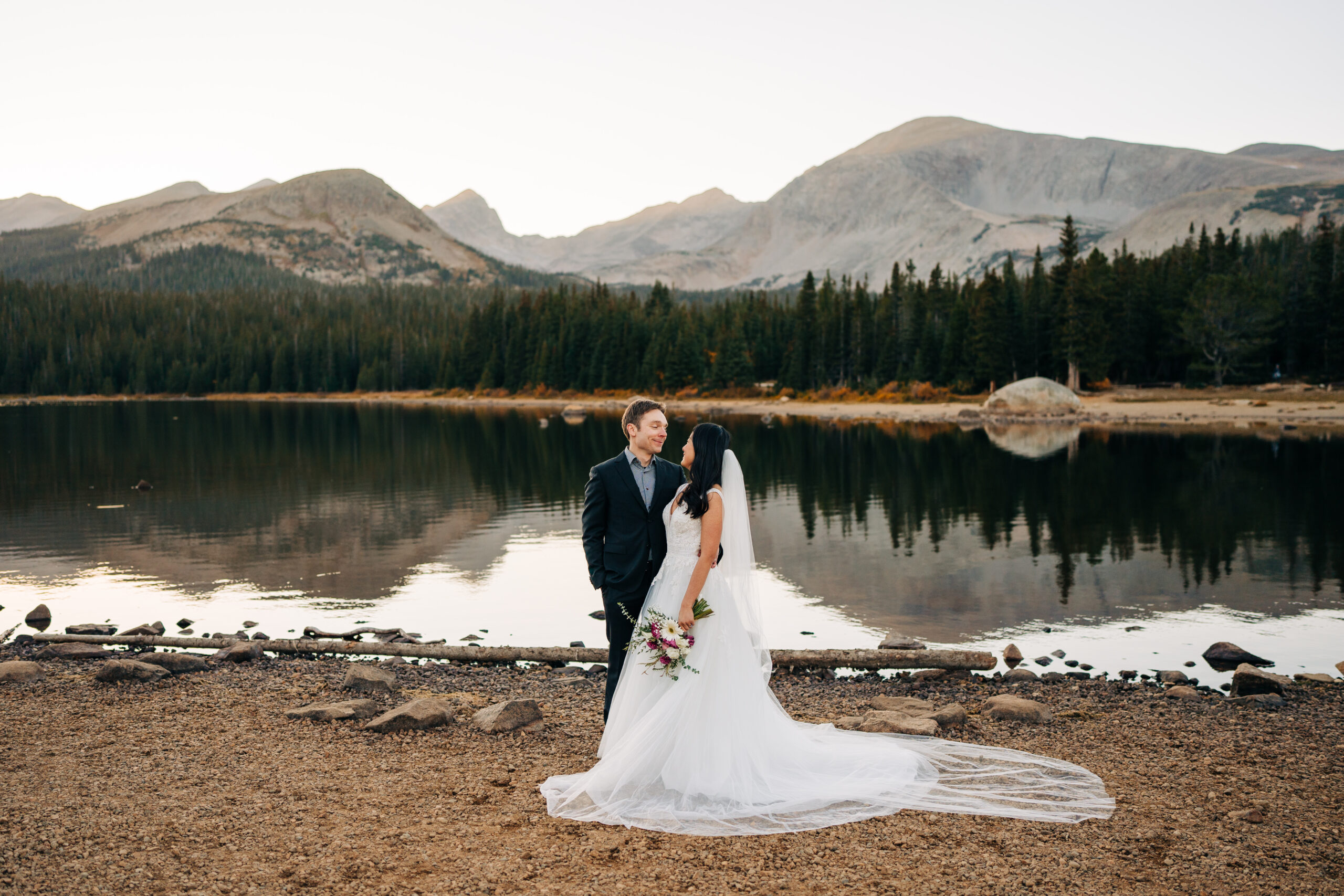 bride and groom holding eachother close and smiling on the lake side during their brainard lake elopement in colorado