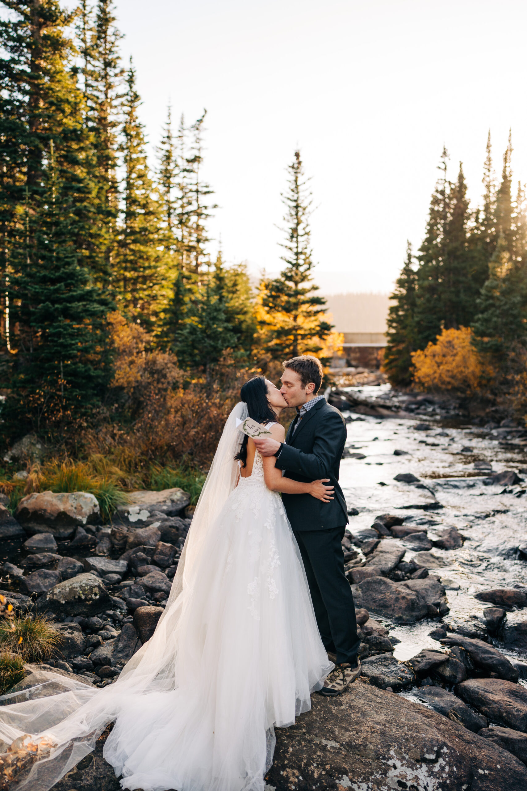 groom kissing bride after reading his vows to her next to a rocky river during their brainard lake elopement