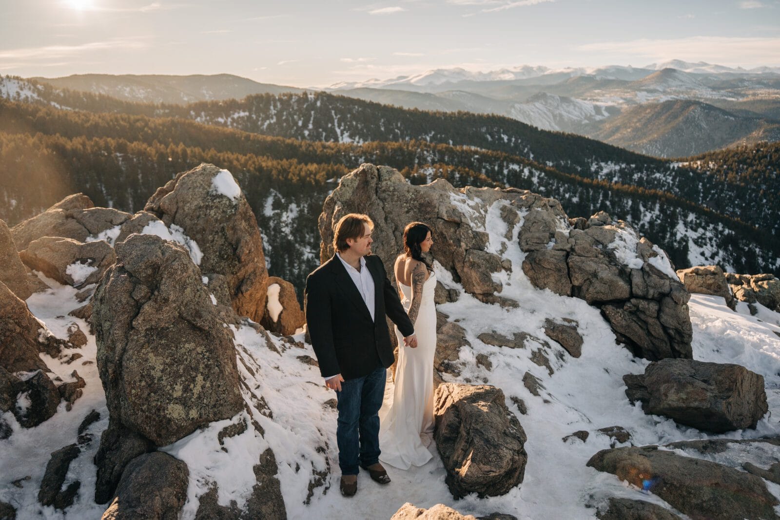 bride and groom holding hands as they watch the sunset over the mountain during their boulder elopement