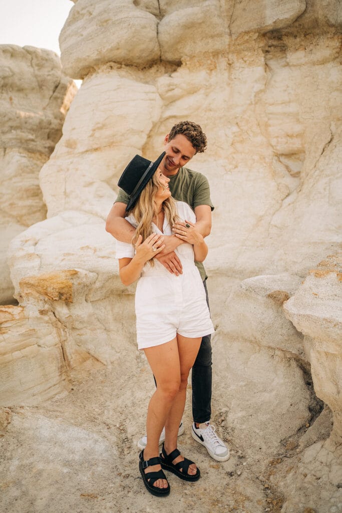 Boyfriend draping arms over girlfriends shoulders during their couples photoshoot at the Colorado Paint Mines