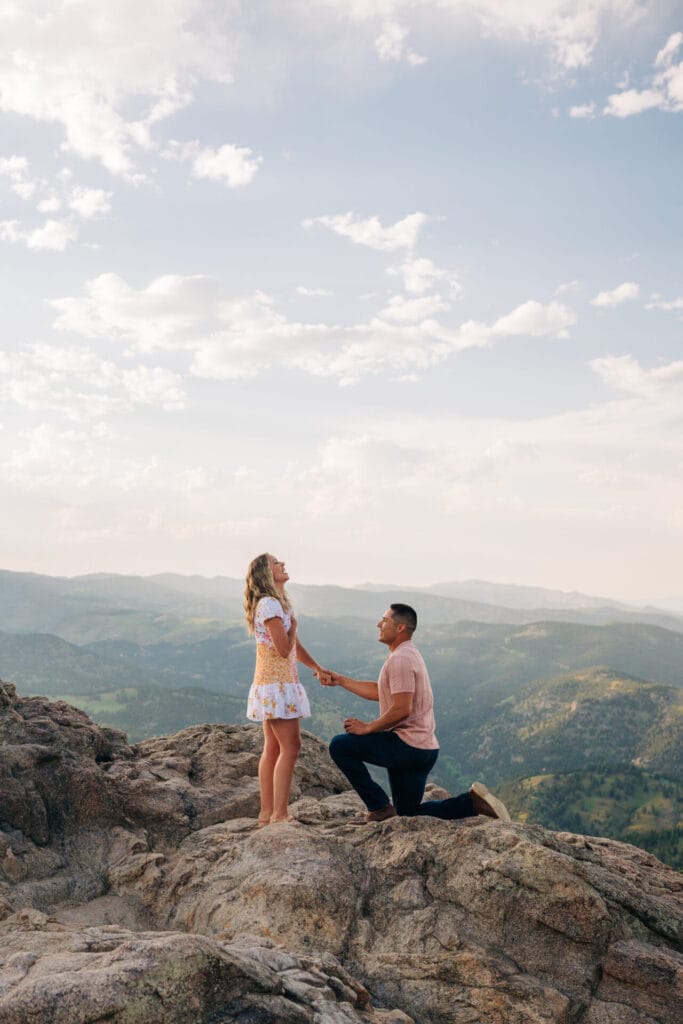 boyfriend holding his girlfriends hand as he proposes on a cliff at Lost Gulch Overlook in Boulder, Colorado