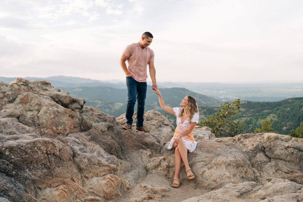 Couple holding hands on rocky mountain overlook during their proposal at Lost Gulch Overlook in Boulder, Colorado