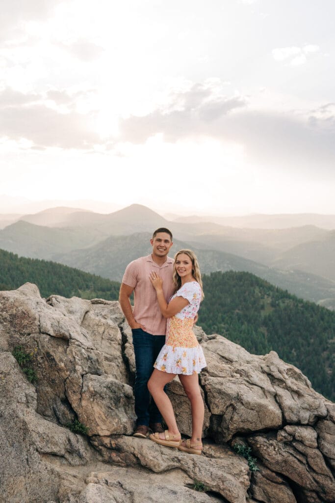 Couple smiling at the camera on a rocky cliff at Lost Gulch Overlook in Boulder, CO