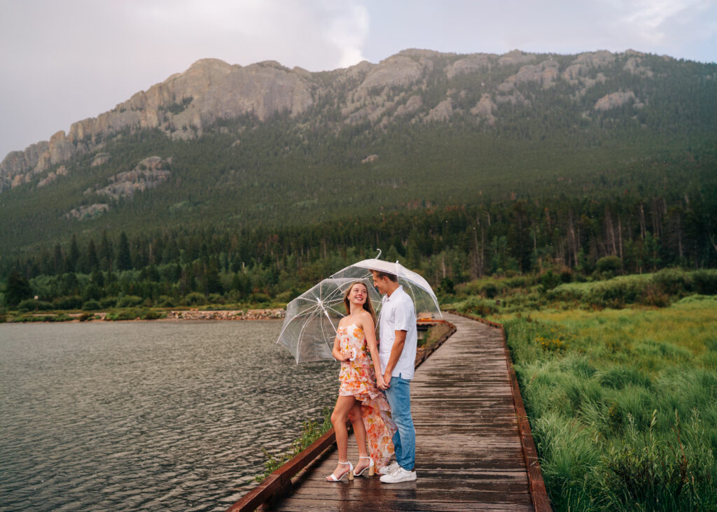 couple holding hands on a boardwalk in the rain during their lily lake engagement photos