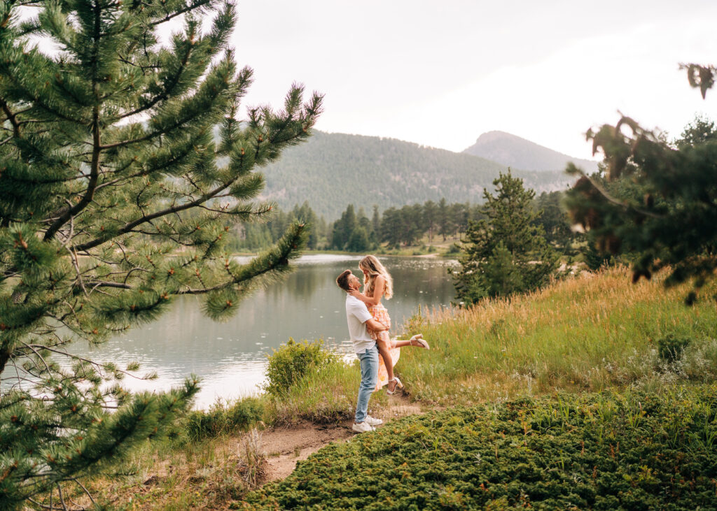 Boyfriend picking his girlfriend up off the ground on the lakeshore during their lily lake engagement photos