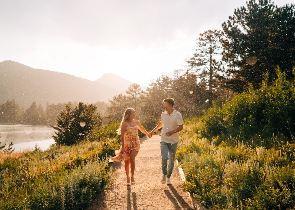 newly engaged couple running down a trail in the rain at sunset during their lily lake engagement photos