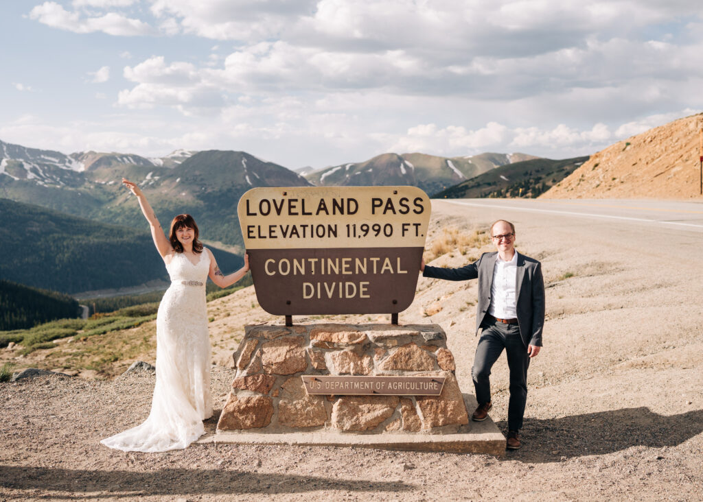 bride and groom standing by the loveland pass sign during their loveland pass elopement