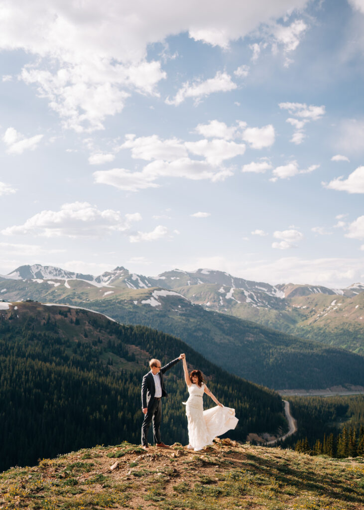 Groom twirling bride in a dance on top of a mountain during their Loveland Pass elopement
