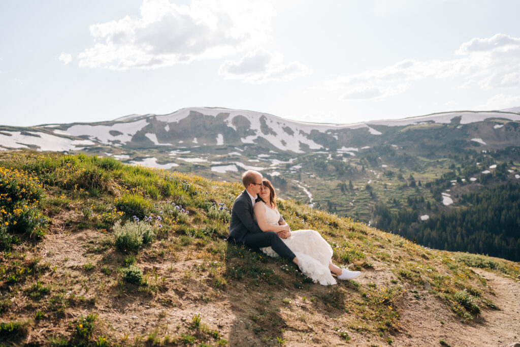bride and groom sitting together on a mountain top meadow during their loveland pass elopement