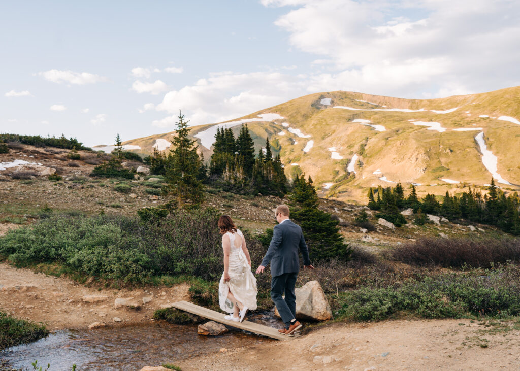 bride and groom walking across a bridge during their loveland pass elopement