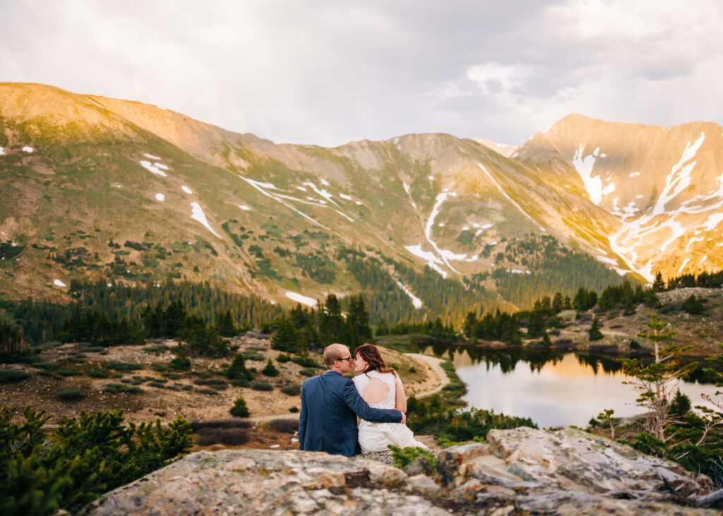 bride and groom sitting together looking out at the mountains during their loveland pass elopement