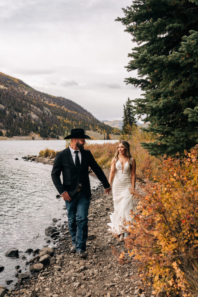 bride and groom walking along the shore of lake san Cristobal during their Lake City Colorado elopement
