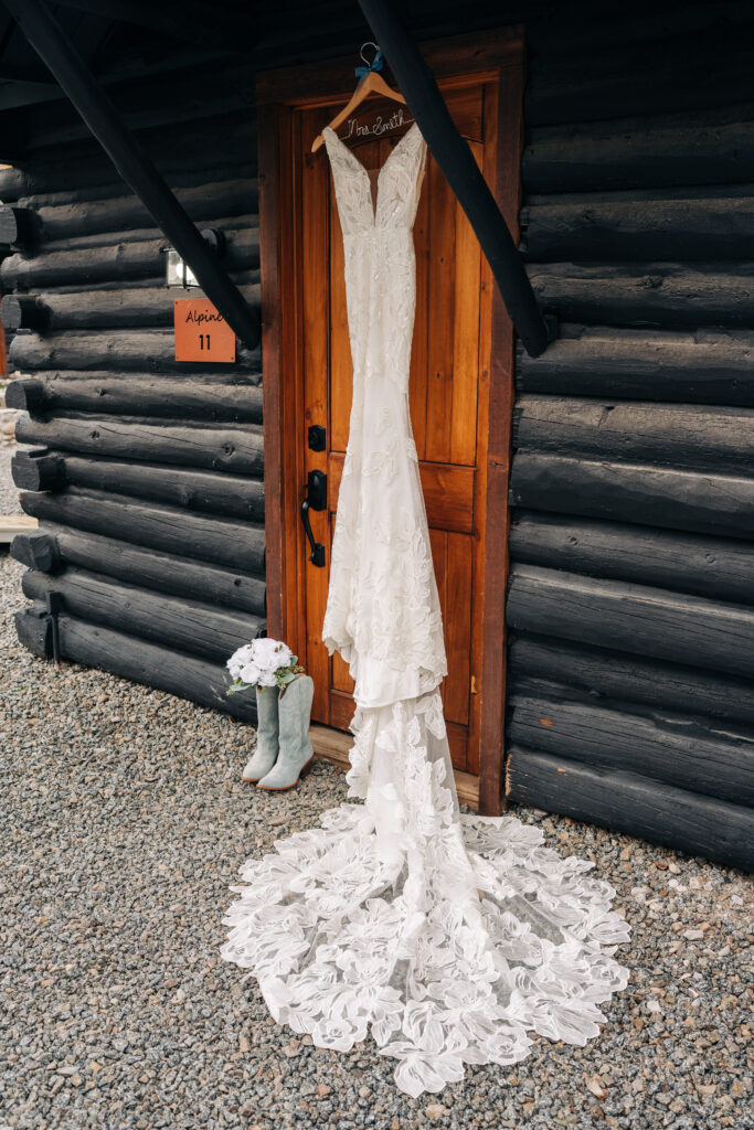brides dress hanging up outside of a cabin at alpine village for their lake city colorado elopement