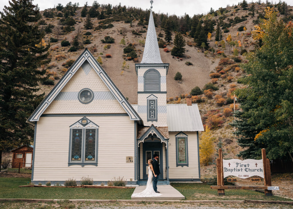 bride and groom holding hands outside small chapel during their lake city colorado elopement