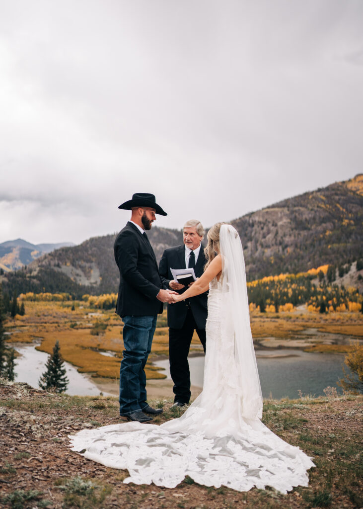 bride and groom holding hands and listening to pastor as they say there wedding vows during the lake city colorado elopement