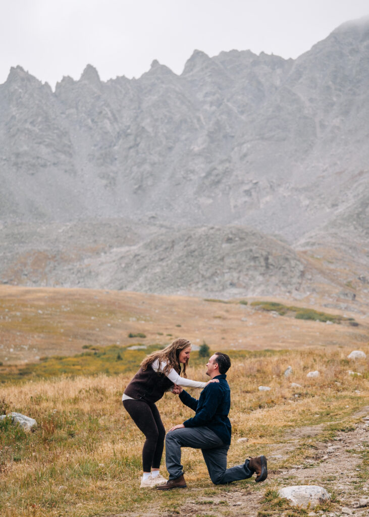 girlfriend bending down to hold her boyfriend who is proposing to her during their mayflower gulch proposal