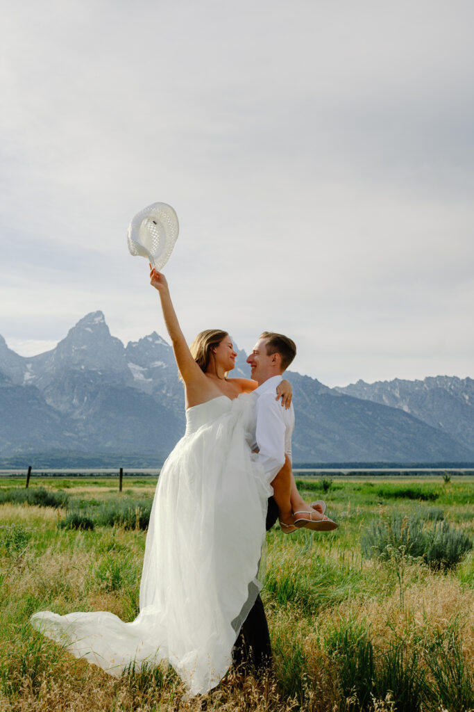 groom holding bride in front of the grand tetons during their elopement