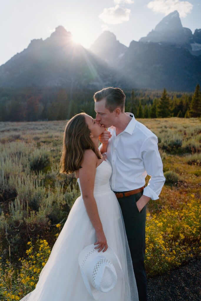 groom holding brides chin while kissing her in front the grand tetons during their elopement