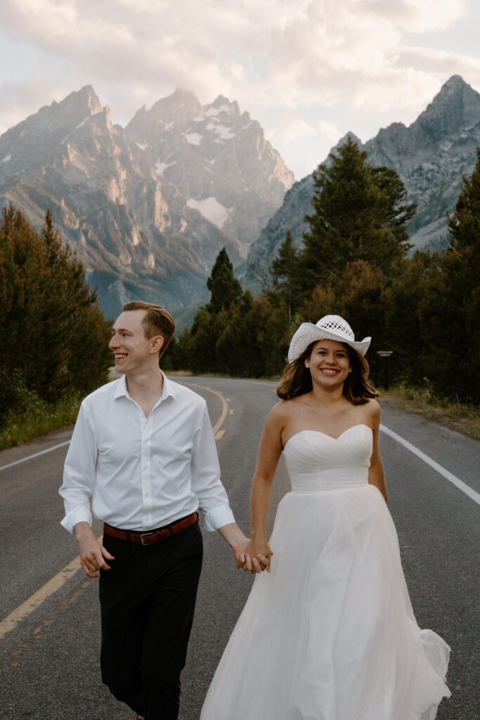 bride and groom running down the road in grand teton national park during their elopement