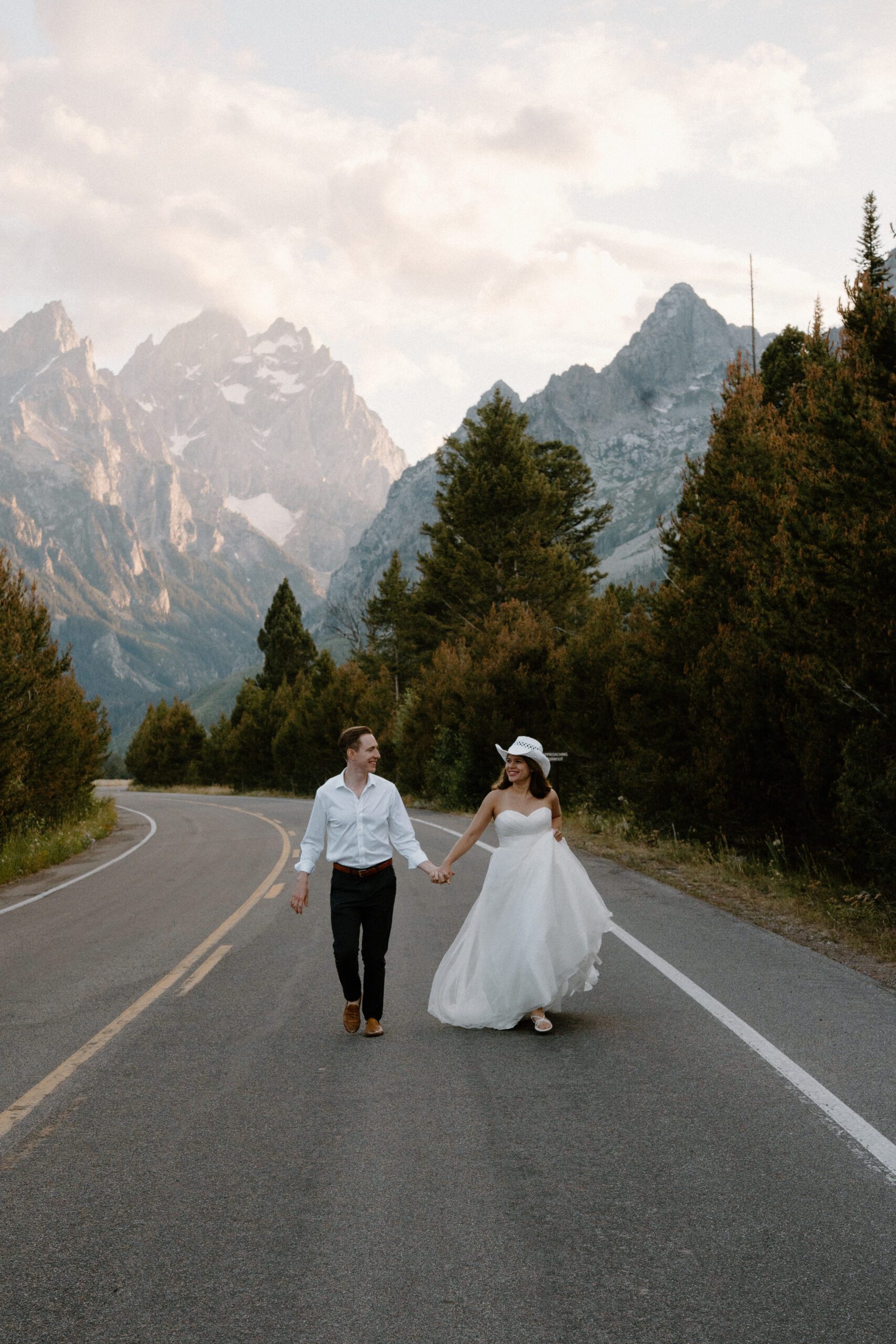 bride and groom running down the road at jenny lake in grand teton national park during their wyoming elopement