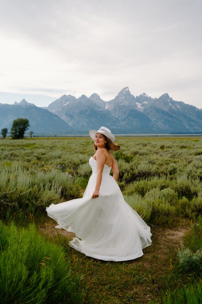 bride twirling in her wedding dress in a field at mormon row at grand tetons national park