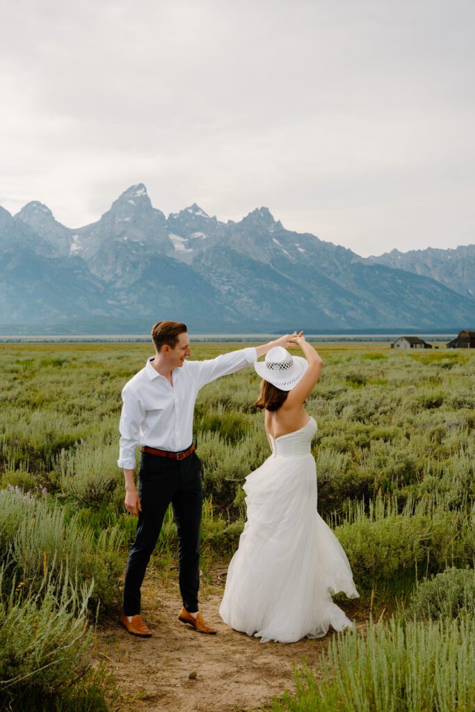 groom twirling bride in a field in grand teton national park during their elopement
