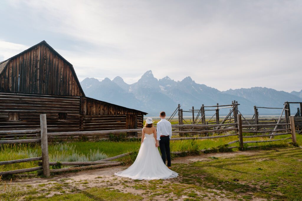 bride and groom facing away from the camera looking at the grand teton mountains during their elopement jackson hole