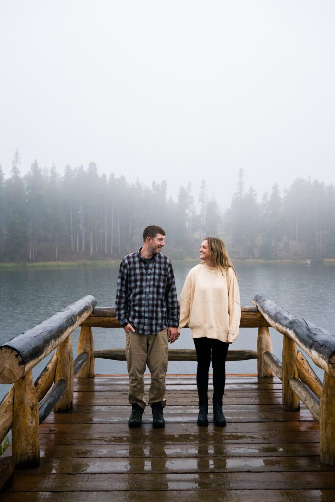 married couple holding hands on the pier at Sprague Lake during their rocky mountain national park engagement session