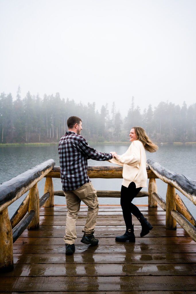 married couple spinning each other around on the pier at Sprague lake during their rocky mountain national park engagement session