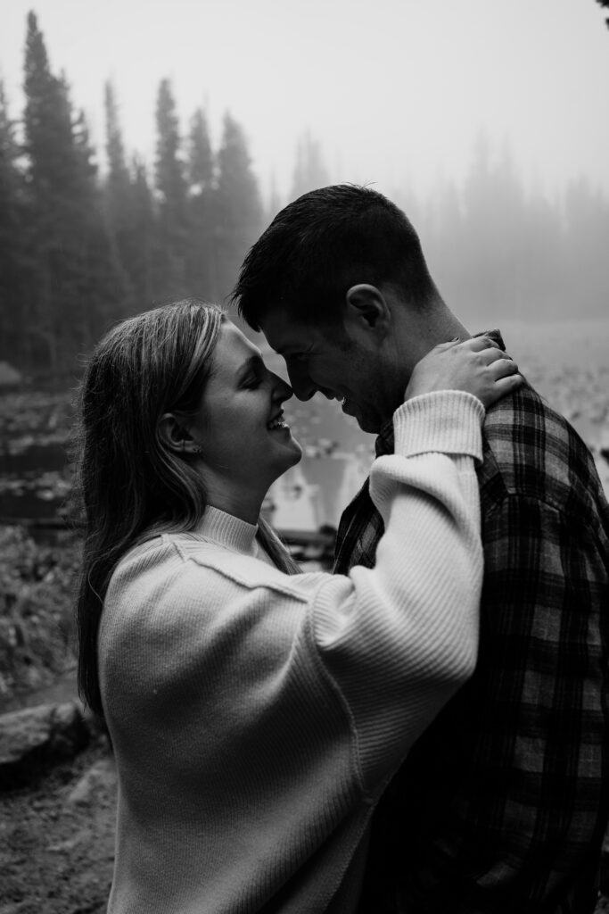 husband and wife nose to nose while standing in the forest during their rocky mountain national park engagement session