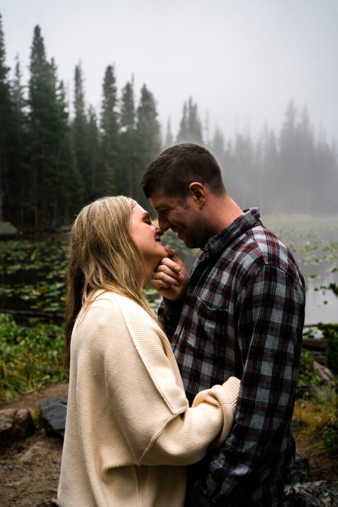 husband holding wives chin as he is about to kiss her during their rocky mountain national park engagement session