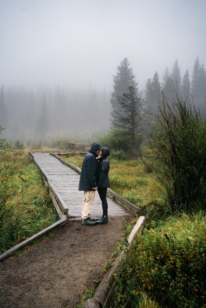 husband and wife holding hands in the rain during their rocky mountain national park engagement session