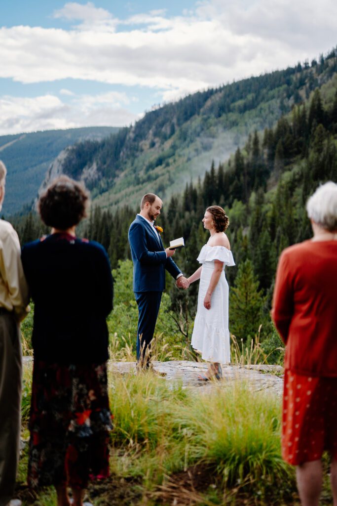 bride and groom holding hands on top of a mountain exchanging their marriage vows during their eldora mountain colorado elopement